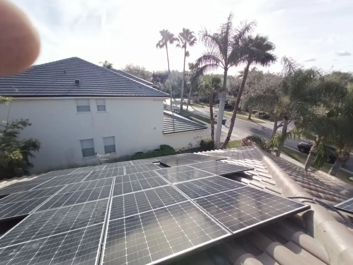Rooftop solar panels re-racked on a tile roof with palm trees behind